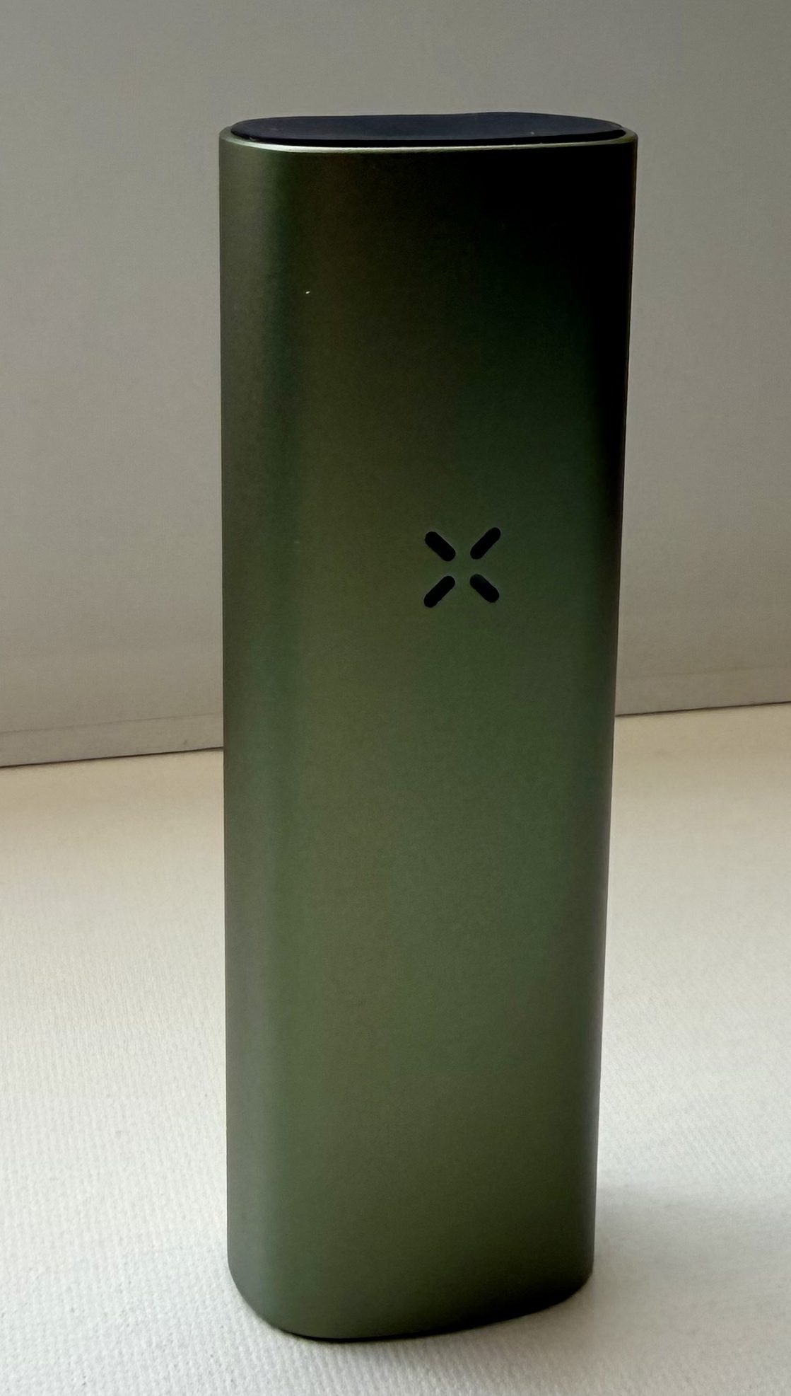 Pax Mini 2, a sleek, vertical vaporizer in a dark green finish with a rounded top and a small logo feature on the front.